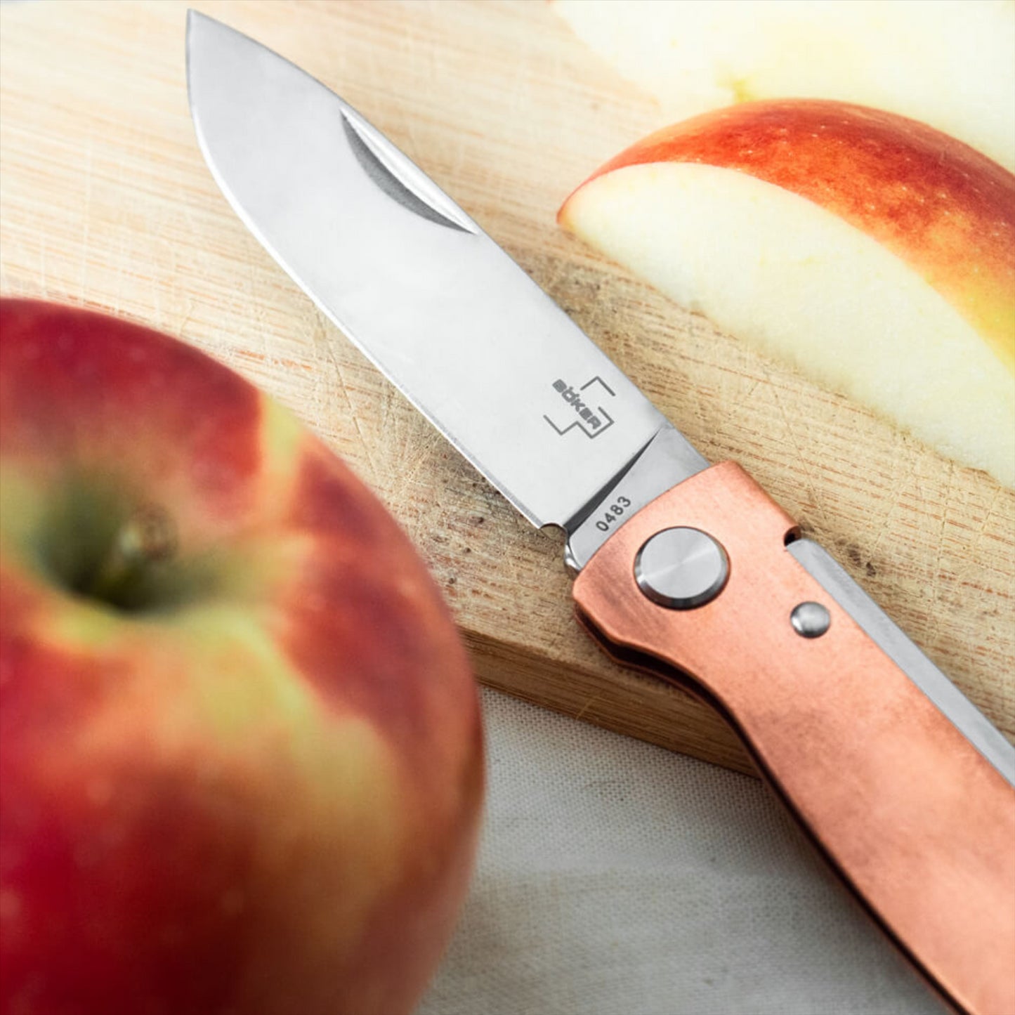 Boker Plus Atlas sulankstomas kišeninis peilis iš 12C27 plieno su varine rankena ant pjaustymo lentos.