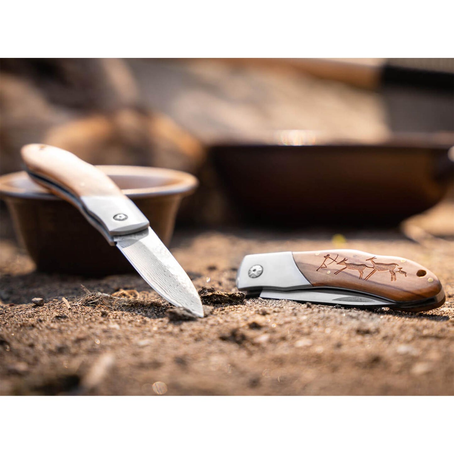 Boker Magnum Caveman sulankstomas peilis su medine rankena, dekoruota medziokles scena, ant zemes pavirsiu